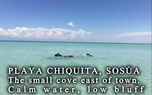 Playa Chiquita cove in Sosúa at mid-morning, calm water inside the reef with condos on the low bluff behind Overlay